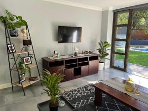 sala de estar con TV y mesa de madera en Afrique134 Baobab Tree Private Family Garden Suite, en Pretoria