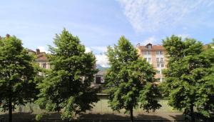 un groupe d'arbres devant un bâtiment dans l'établissement Le petit Versailles - T2 au centre-ville, à Grenoble