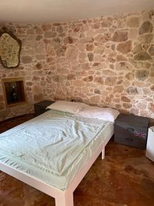 een bed in een kamer met een stenen muur bij La traversa in Sannicola