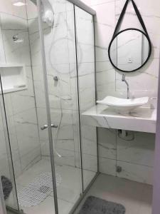 a bathroom with a shower with a sink and a mirror at Studio Wifi Tv Ar-condicionado Orla Conforto in Petrolina