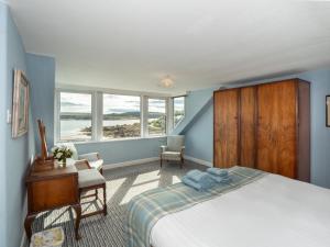 a bedroom with a bed and a desk and windows at Neptune Cottage in Rockcliffe