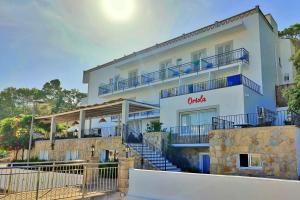 a white building with blue balconies and stairs at Boutique Hotel Oriola in Cala de Sant Vicenc