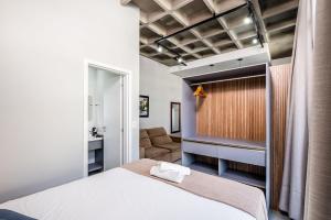 um quarto com uma cama branca e um sofá em Top Studios Canasvieiras TPS em Florianópolis