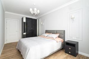 a white bedroom with a bed and a chandelier at Premium Apartment Chisinau in Chişinău