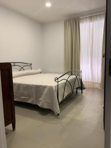 Un dormitorio blanco con una cama y una ventana. en La Masseria di Felicetta, en SantʼAnastasia