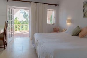 1 dormitorio con cama blanca y balcón en Hurricane Beach Hotel, en Tarifa