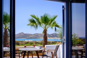 a room with a view of the ocean and a palm tree at White Dream Suites Antiparos in Antiparos