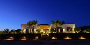 a house with palm trees and lights at night at White Dream Suites Antiparos in Antiparos