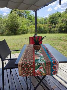 einen Tisch mit einem bunten Tischtuch auf einem Deck in der Unterkunft Le kota des 3 tilleuls in Dampierre-sur-Salon