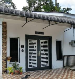 eine Eingangstür eines weißen Hauses mit einer schwarzen Tür in der Unterkunft Kampung Vibe @ Homestay Baiduri in Slim River