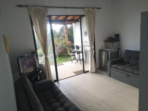 uma sala de estar com um sofá e uma porta de vidro deslizante em Villa Namaste, Cabaña Namaste 1 em Curití