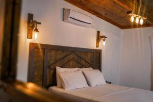 een slaapkamer met een bed met een houten hoofdeinde en verlichting bij Belong Butik Otel in Çeşme