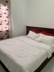 1 cama con sábanas blancas y almohadas rojas en Homestay Bajet MokAji, en Kuala Terengganu