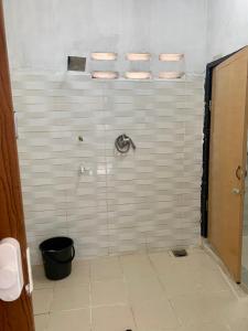 y baño con ducha y paredes de azulejos blancos. en Homestay Bajet MokAji, en Kuala Terengganu