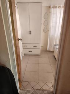 a hallway with a white cabinet and a tiled floor at Valdu Cozy Cottage in Christ Church
