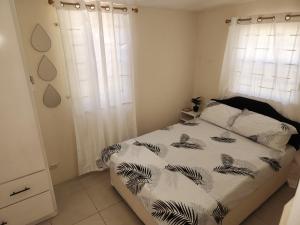 Schlafzimmer mit einem Bett mit einer schwarzen und weißen Bettdecke in der Unterkunft Valdu Cozy Cottage in Christchurch