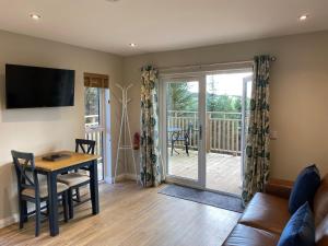 a living room with a table and a sliding glass door at Acorn Lodge with Hot Tub in Cupar