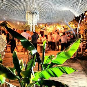 a crowd of people standing around a bar with a chandelier at guinguette pour faire la fête in Saint-Laurent-dʼAigouze