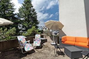 a patio with an orange couch and chairs and an umbrella at Appartement Arend in Dobel