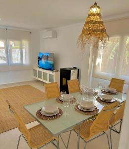 een eetkamer met een tafel met stoelen en een kroonluchter bij Bonaire Beach House in Alcudia