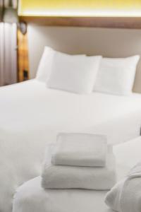 - un lit avec des draps blancs et des serviettes dans l'établissement L'Elysée Val d'Europe, à Serris