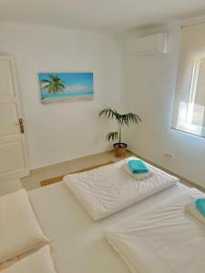 een wit bed in een kamer met een potplant bij Bonaire Beach House in Alcudia