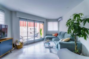 een woonkamer met een blauwe bank en een tv bij Palangre Beach Apartment in Torrevieja