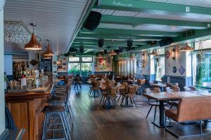 a restaurant with tables and chairs and a bar at De Welvaart - Logement in Hollum