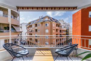 twee stoelen op een balkon met uitzicht op een gebouw bij Palangre Beach Apartment in Torrevieja