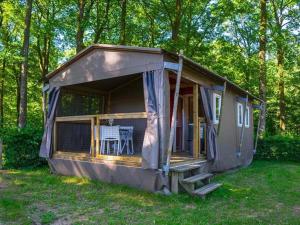 a small house with a porch and a table at Camping de la Forêt Seasonova in Sillé-le-Guillaume