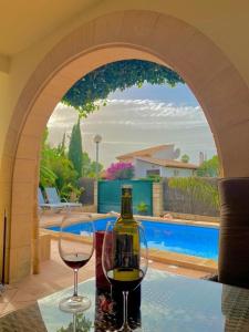 Una botella de vino y dos copas en una mesa cerca de una piscina. en Bonaire Beach House, en Alcudia