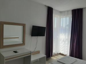 ein Hotelzimmer mit einem TV und einem Fenster in der Unterkunft Апартаменти Жени in Zarewo