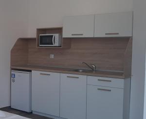 cocina con armarios blancos y microondas en Апартаменти Жени, en Tsarevo
