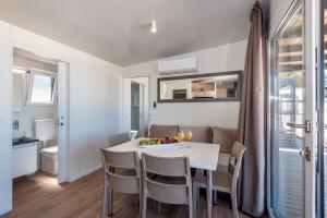 普利莫顿CAMP ADRIATIC MOBILE HOMES - PRIMOŠTEN的厨房和餐厅配有白色桌子和椅子