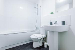 een witte badkamer met een wastafel en een toilet bij 2 Bed apartment with balcony private parking near Etihad Stadium, COOP Live in Manchester