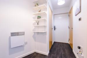 a hallway with white walls and a door with shelves at 2 Bed apartment with balcony private parking near Etihad Stadium, COOP Live in Manchester