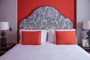 a bed with two red pillows and a black and white headboard at Maalot Roma - Small Luxury Hotels of the World in Rome