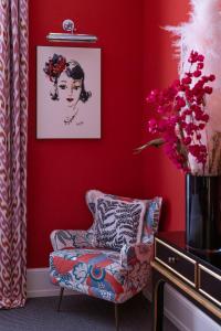 a red living room with a chair and a vase of flowers at Maalot Roma - Small Luxury Hotels of the World in Rome