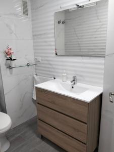 ein Badezimmer mit einem Waschbecken, einem WC und einem Spiegel in der Unterkunft Isla 1.1 in Santa Pola