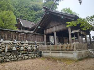 a wooden building with a fence and a stone wall at Fukubatake B&B in Yoshino