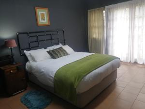 um quarto com uma cama grande e um cobertor verde em Oteng Guest House em Belfast