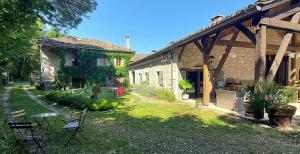 a house with a yard with tables and chairs at Le Moulin de Bernard in Saint-Pantaléon