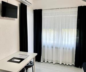Habitación con mesa y ventana con cortinas. en Rooms Mirabella, en Rakovica