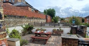 a patio with a wooden table and a brick wall at Central Ripon apartment - view of the Cathedral! in Ripon