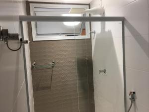 eine Dusche mit Glastür und Fenster in der Unterkunft Apto Luxo frente praia do Morro in Guarapari + 23 Fotos