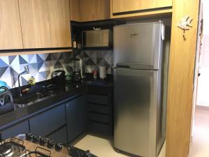 eine Küche mit einem Kühlschrank aus Edelstahl und einer Spüle in der Unterkunft Apto Luxo frente praia do Morro in Guarapari