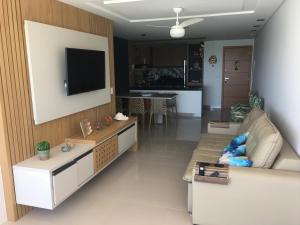 ein Wohnzimmer mit einem Sofa und einem Fernseher an der Wand in der Unterkunft Apto Luxo frente praia do Morro in Guarapari