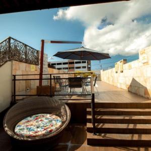 a grill on a balcony with a table and an umbrella at Happy Hotel Brisa do Mar in Ipojuca