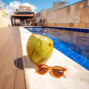 a coconut with sunglasses next to a swimming pool at Happy Hotel Brisa do Mar in Ipojuca