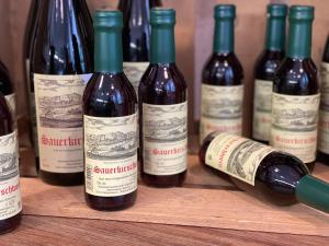 a group of wine bottles sitting on a wooden shelf at Bauerngarten in Hofgeismar